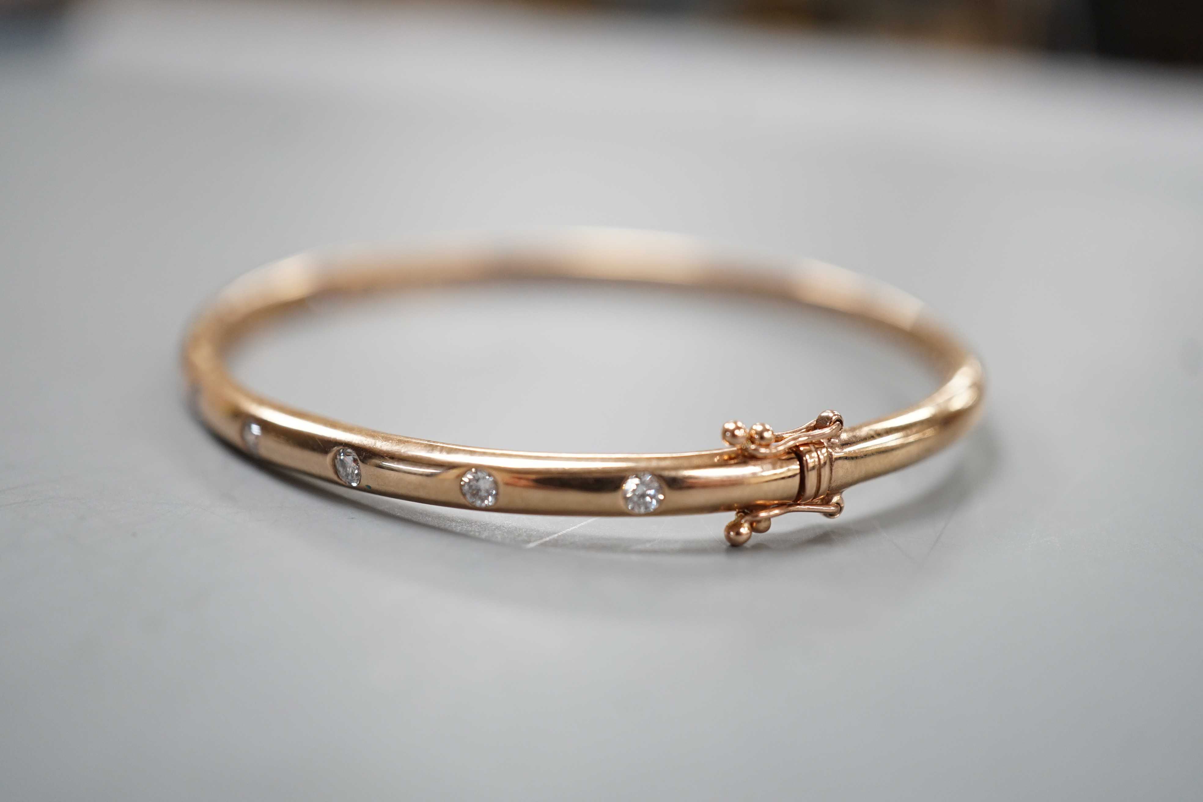 A modern 9k and nine stone gypsy set diamond hinged bangle, interior diameter 60mm, gross weight 9.3 grams.